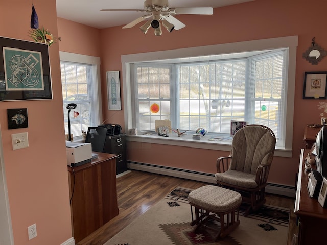 office space with a baseboard heating unit, dark wood finished floors, and a ceiling fan