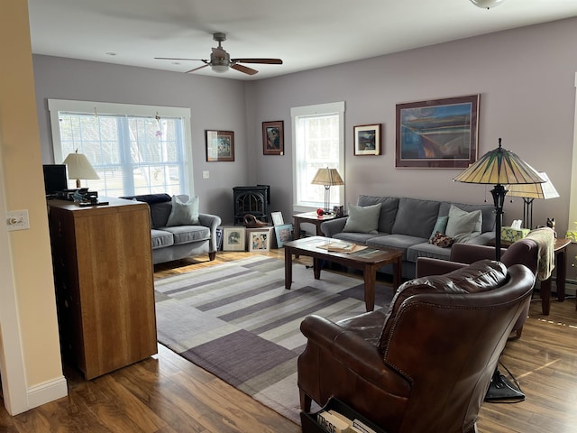 living area with a wealth of natural light, a wood stove, and wood finished floors