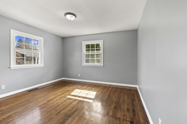 empty room with visible vents, baseboards, and wood-type flooring