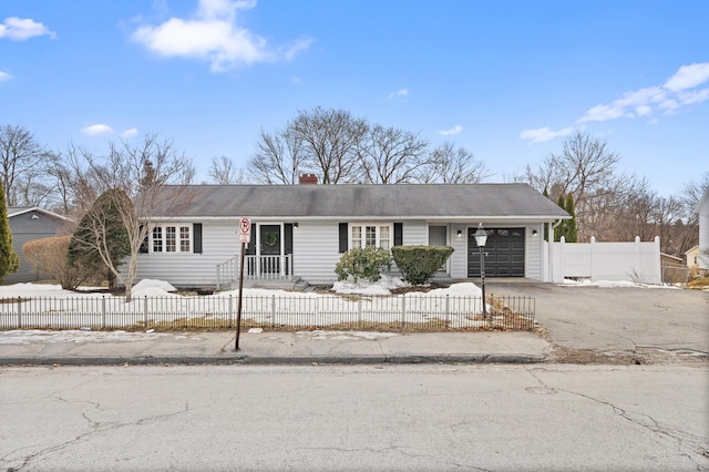 ranch-style home with a fenced front yard, an attached garage, and aphalt driveway