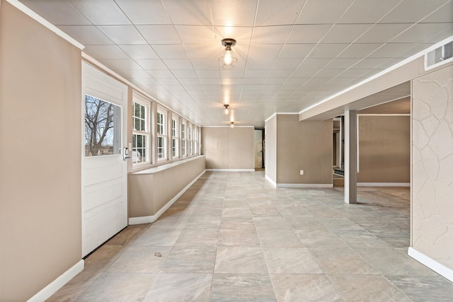 empty room featuring baseboards, visible vents, and ornamental molding