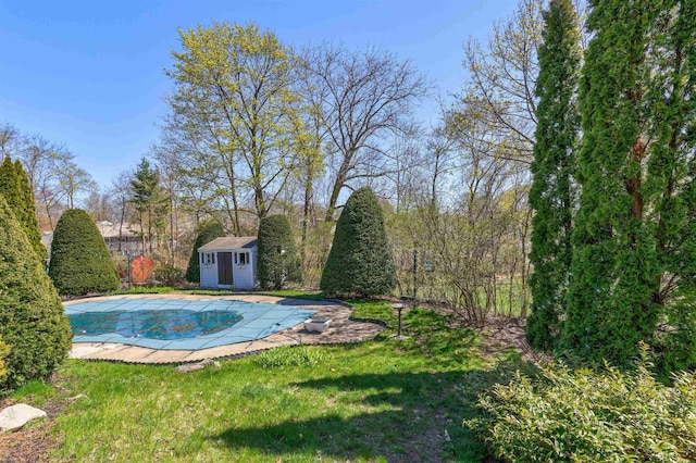 view of swimming pool with a storage unit, a covered pool, an outbuilding, and a lawn