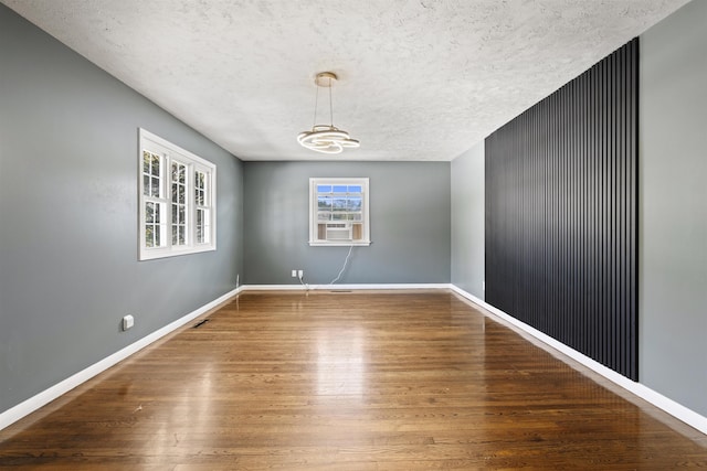 spare room with cooling unit, baseboards, a textured ceiling, and wood finished floors