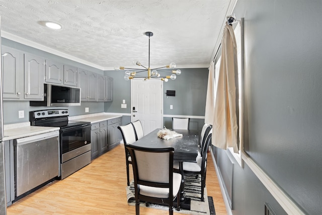 kitchen featuring light wood-type flooring, stainless steel appliances, gray cabinetry, and light countertops