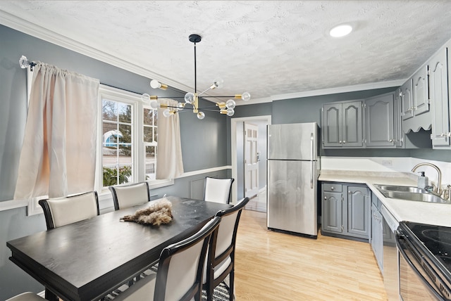 kitchen featuring gray cabinetry, ornamental molding, a sink, freestanding refrigerator, and light wood-style floors