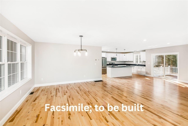 unfurnished living room featuring visible vents, baseboards, a chandelier, and light wood finished floors