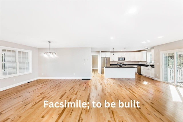 kitchen with stainless steel appliances, white cabinetry, dark countertops, and light wood finished floors