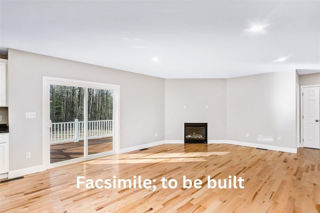 unfurnished living room featuring a glass covered fireplace, baseboards, visible vents, and light wood finished floors