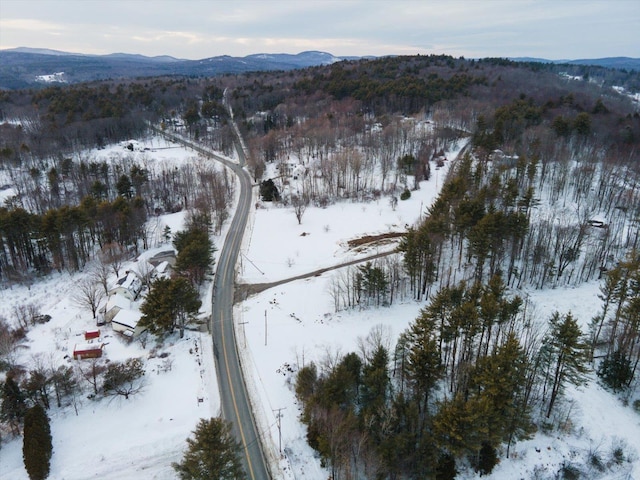 snowy aerial view featuring a view of trees and a mountain view