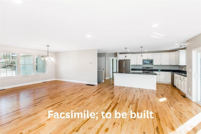 kitchen featuring dark countertops, light wood-style flooring, white cabinetry, and stainless steel appliances