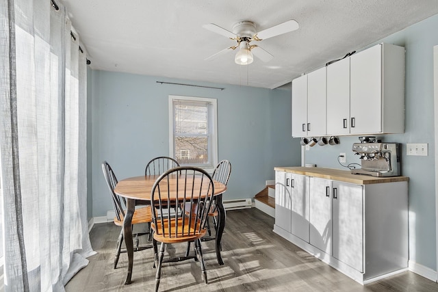 dining area featuring a ceiling fan, wood finished floors, baseboards, a textured ceiling, and baseboard heating