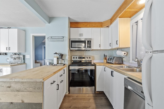 kitchen with dark wood-type flooring, decorative backsplash, appliances with stainless steel finishes, white cabinetry, and a sink