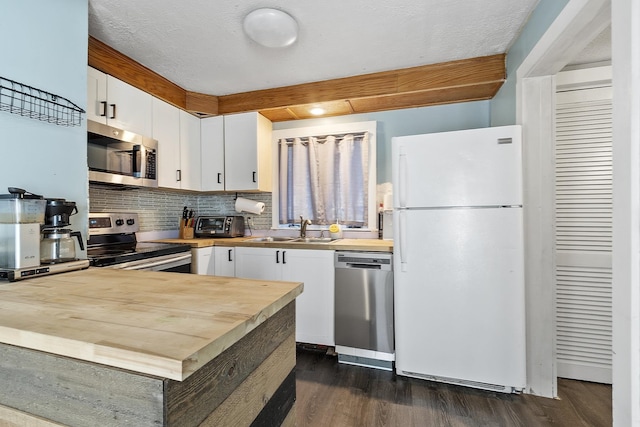 kitchen featuring a sink, appliances with stainless steel finishes, white cabinets, decorative backsplash, and dark wood-style flooring