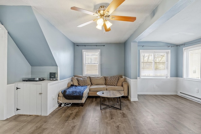 sitting room with wood finished floors, ceiling fan, vaulted ceiling, a textured ceiling, and a baseboard heating unit