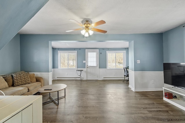 living area with dark wood finished floors, a wealth of natural light, and a baseboard radiator