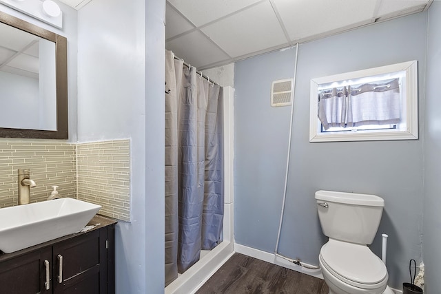 full bath with curtained shower, wood finished floors, toilet, and a paneled ceiling