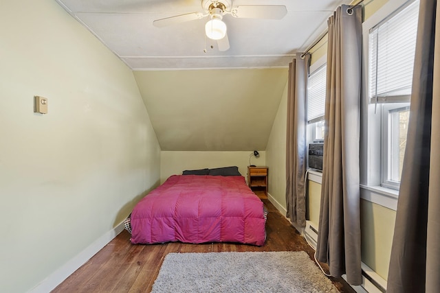 bedroom with lofted ceiling, a ceiling fan, a baseboard heating unit, wood finished floors, and baseboards