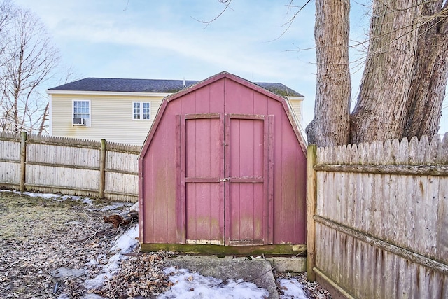 snow covered structure with an outdoor structure, fence, and a shed