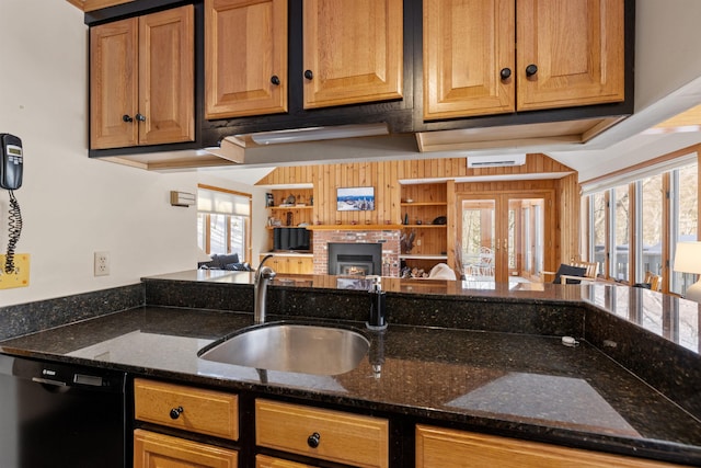 kitchen featuring dishwasher, dark stone counters, a fireplace, and a sink