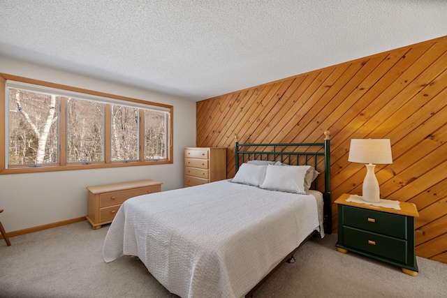 bedroom featuring carpet flooring, baseboards, wood walls, and a textured ceiling