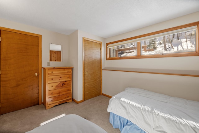 carpeted bedroom featuring multiple windows, baseboards, a closet, and a textured ceiling