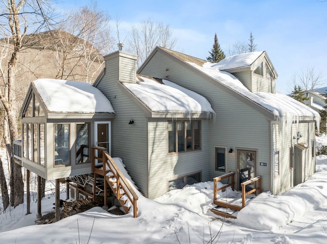 snow covered rear of property featuring a chimney