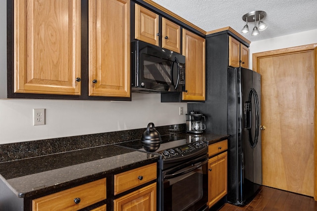 kitchen featuring dark stone countertops, a textured ceiling, black appliances, and dark wood-style flooring