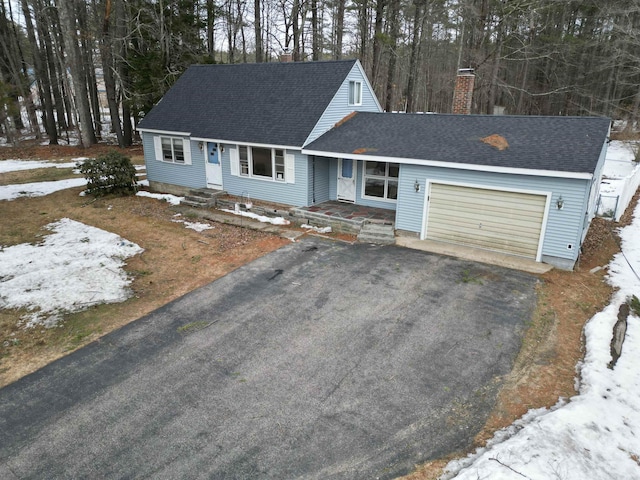 view of front of property featuring aphalt driveway, a chimney, a shingled roof, and an attached garage