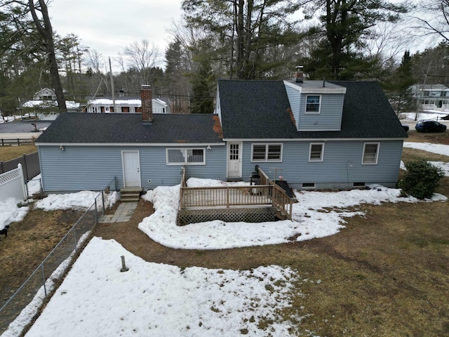 snow covered rear of property with a shingled roof, fence, entry steps, a chimney, and a deck