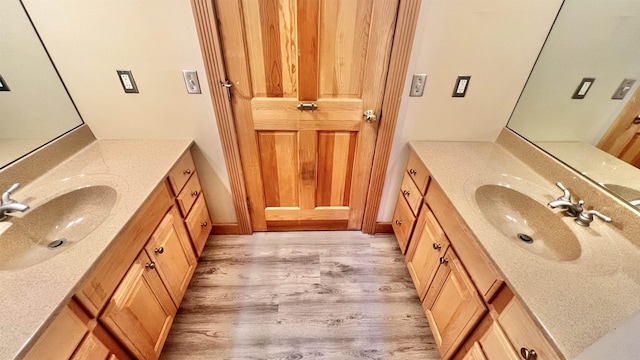 bathroom featuring wood finished floors, two vanities, and a sink