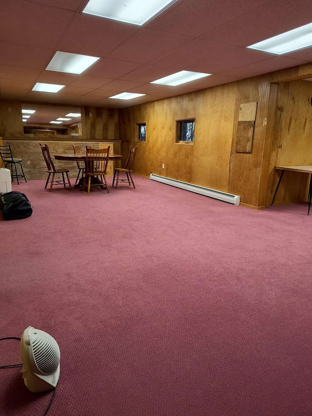 interior space featuring a baseboard heating unit, wooden walls, and a drop ceiling