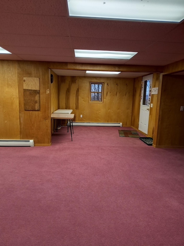 finished basement featuring wooden walls, carpet flooring, and a drop ceiling