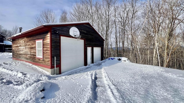 snow covered garage with a detached garage