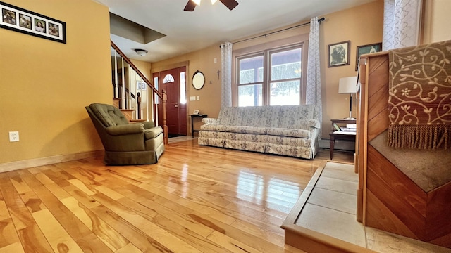 sitting room with a baseboard heating unit, ceiling fan, stairs, and hardwood / wood-style flooring