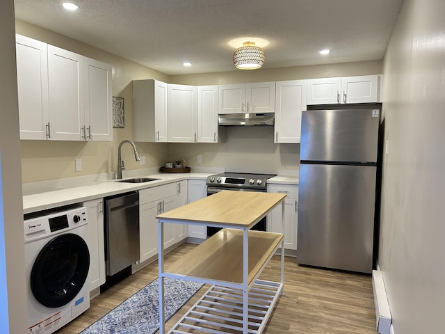 kitchen with a sink, under cabinet range hood, washer / clothes dryer, stainless steel appliances, and light countertops