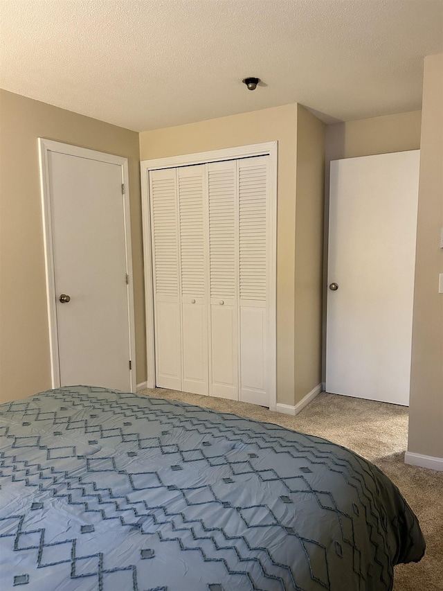 unfurnished bedroom featuring carpet flooring, baseboards, a closet, and a textured ceiling