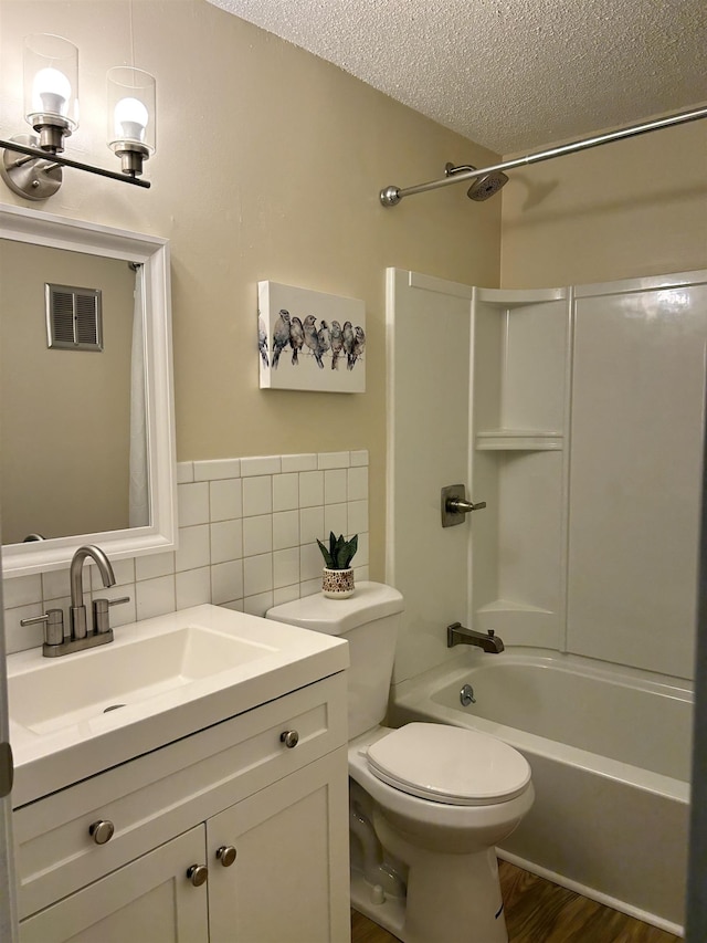 full bath with toilet, a textured ceiling, wood finished floors, tub / shower combination, and vanity