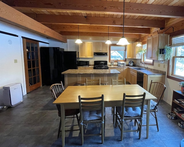 kitchen featuring black appliances, a healthy amount of sunlight, under cabinet range hood, and a center island