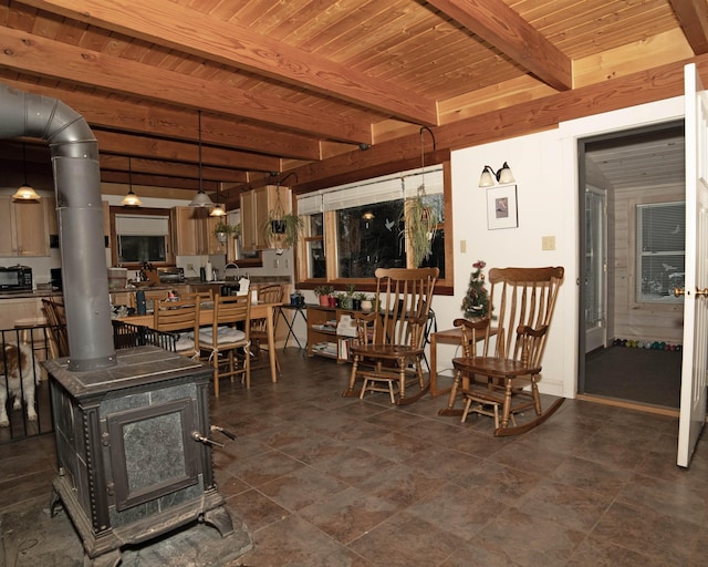 dining area featuring beamed ceiling, wood ceiling, and a wood stove