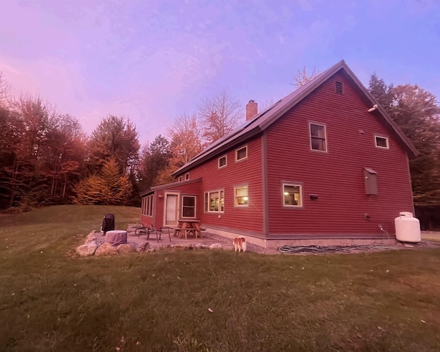 rear view of property with a lawn, a chimney, and a patio area