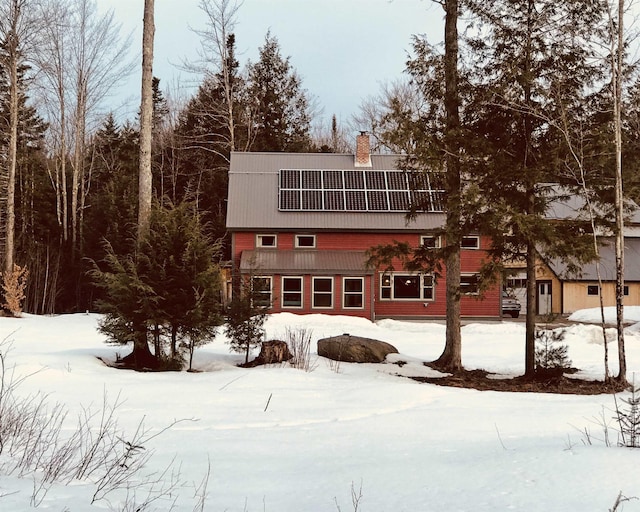 view of front of home featuring a gambrel roof, roof mounted solar panels, and a chimney