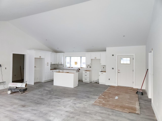 kitchen featuring light wood-style flooring, high vaulted ceiling, white cabinets, and a center island