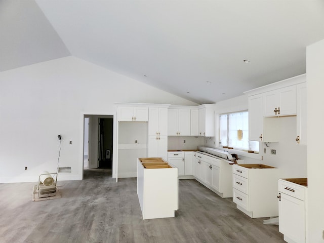 kitchen featuring light wood-style flooring, white cabinets, a kitchen island, and lofted ceiling