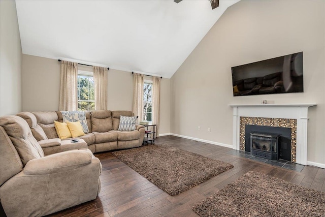 living area featuring a tiled fireplace, baseboards, dark wood-style flooring, and high vaulted ceiling