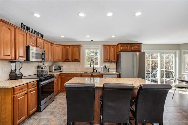 kitchen featuring a kitchen bar, a sink, tasteful backsplash, a center island, and stainless steel appliances