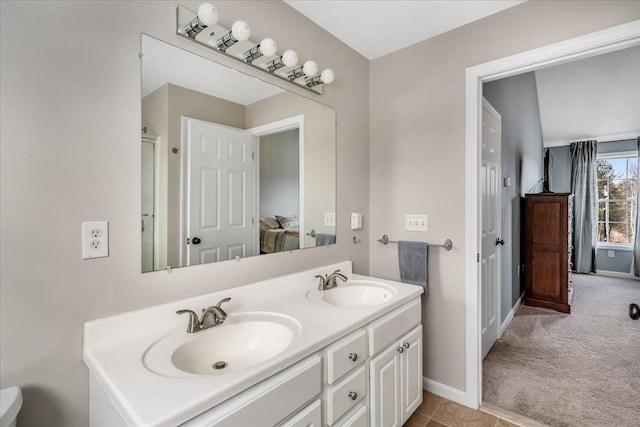 full bath featuring double vanity, ensuite bathroom, baseboards, and a sink