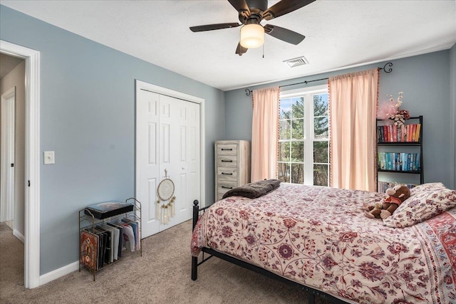 carpeted bedroom with visible vents, baseboards, a closet, and a ceiling fan