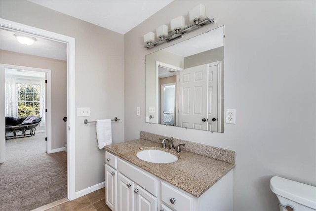 half bath with baseboards, toilet, ensuite bathroom, and vanity