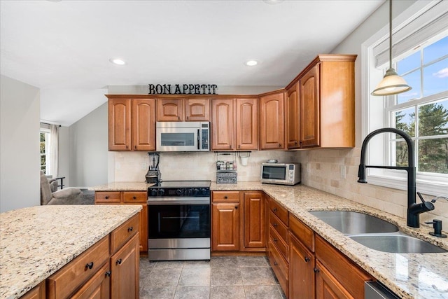 kitchen featuring a sink, stainless steel appliances, decorative backsplash, light stone countertops, and hanging light fixtures