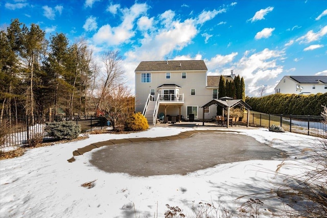 snow covered house featuring stairway and fence